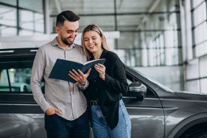 Young couple choosing a car in a car show room