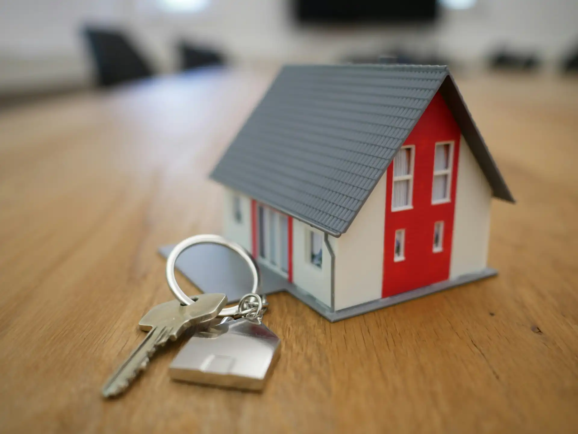 Imagem de uma casa em miniatura com chave e porta ao lado, representando o mercado imobiliário, tendências, desafios e oportunidades para os próximos anos.