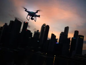 Drone sobrevoando arranha-céus ao entardecer, simbolizando as indústrias autônomas e novas oportunidades para empresas globais no setor tecnológico.