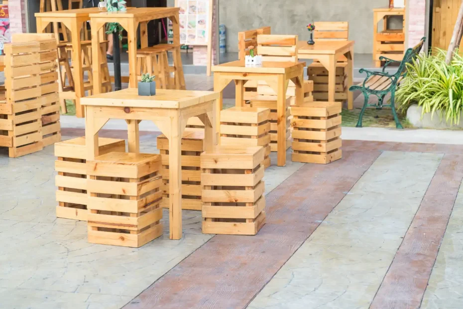 Móveis de pallet de madeira usados como alternativa sustentável para mobiliar o espaço externo, incluindo mesas e bancos em um ambiente ao ar livre.