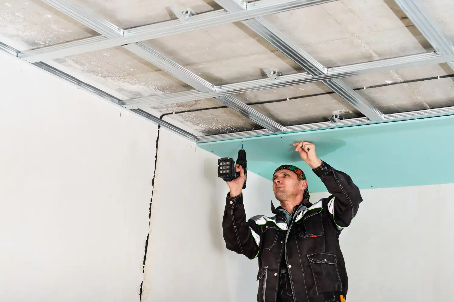 Instalador de forro de PVC, drywall e gesso em andamento com ferramentas elétricas em obra residencial, comparando diferenças de materiais.
