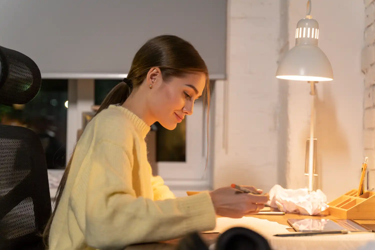 Mulher estudando dicas para reduzir a conta de luz em casa e no comércio, sentado na mesa com iluminação adequada e ambiente confortável.
