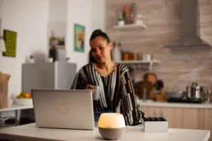 Mulher em home office ajustando postura para ergonomia doméstica, com notebook e iluminação adequada, promovendo saúde e conforto no trabalho remoto.